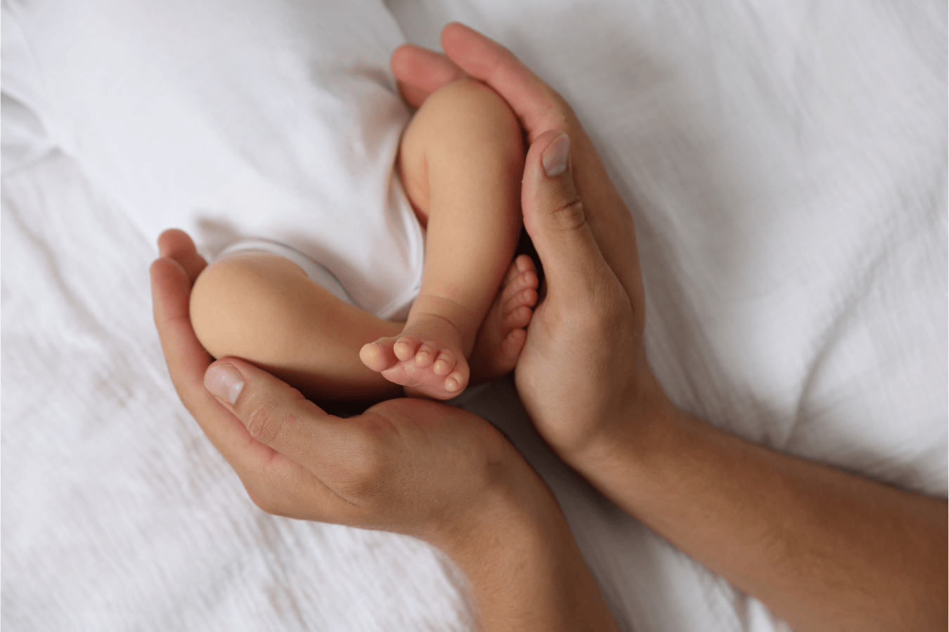 Mãos de mãe segurando o pezinho do bebê recém-nascido